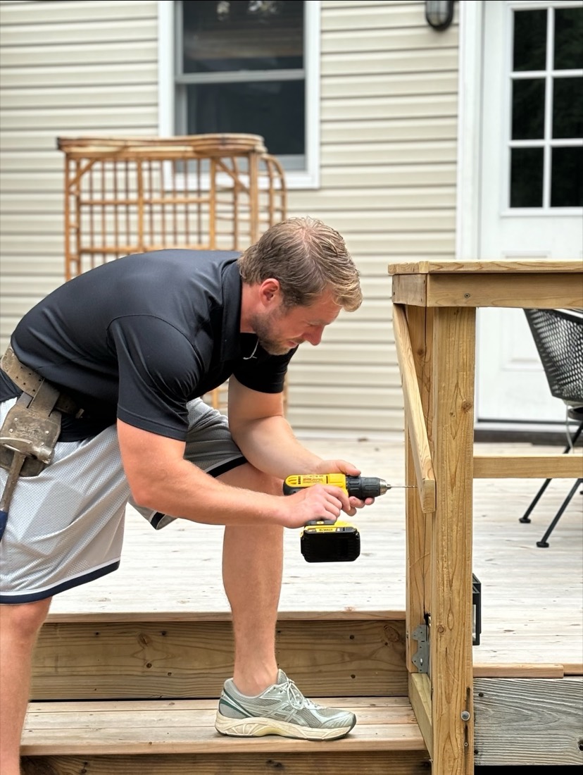 A Nielsen team member with a tool belt building out a deck railing at a client's home.